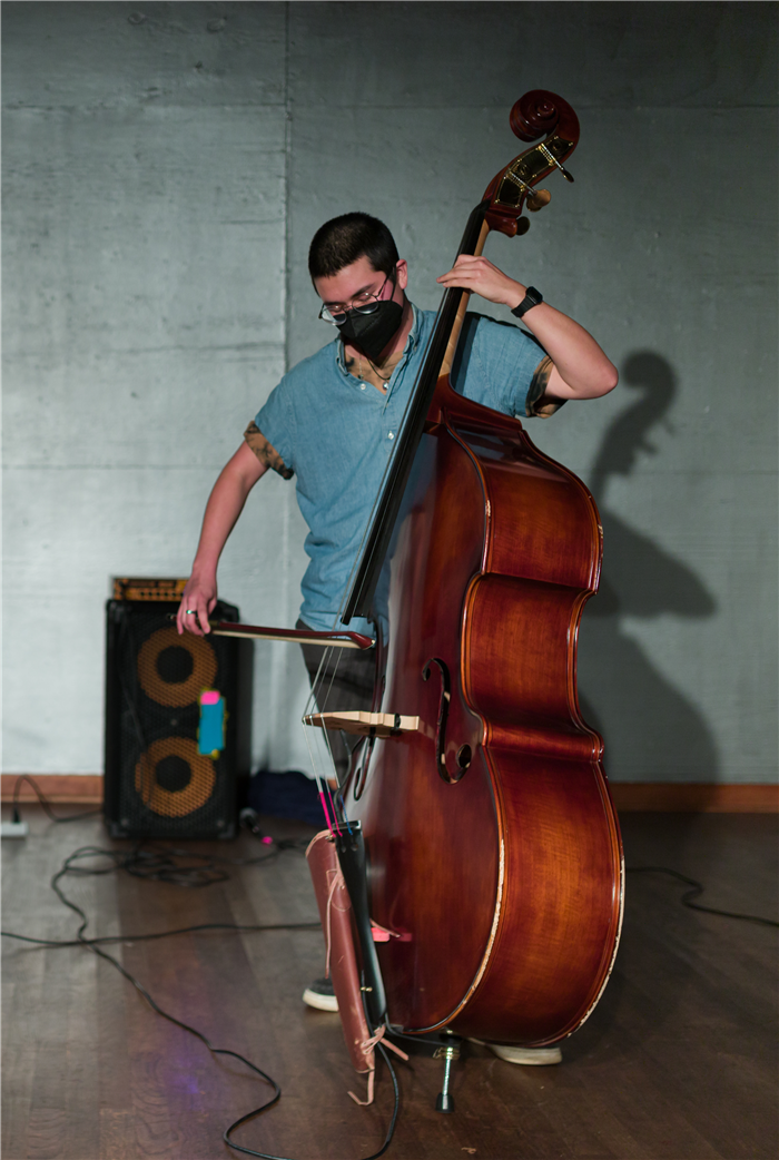 Kumi Maxson playing upright bass with a bow.